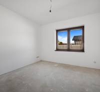 Corner room in a family house with a window, white walls, and spacious area.