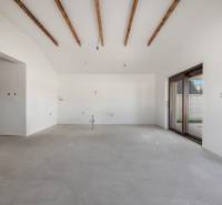 A spacious room in a family house with white walls and wooden beams on the ceiling.