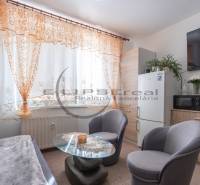 Living area of a studio apartment with a sofa, table, and colorful curtains.