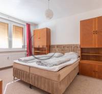 A bedroom with a bed and wooden furniture in a studio apartment, curtains on the windows.