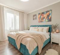 Bedroom in a 2-room apartment with a bed, paintings, and a wooden decor floor.