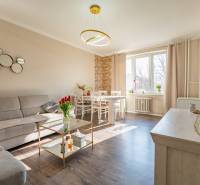 Living room with a corner sofa, dining table, and wooden decor flooring in a two-room apartment.