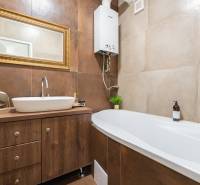 Bathroom with a bathtub and a sink in a 2-room apartment, floor with wooden decor.