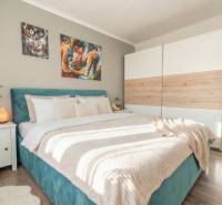 A bedroom with a bed, a wardrobe, and a wooden decor floor in a two-room apartment.