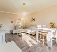A bright living room with white furniture and a wood-patterned floor in a 2-room apartment.