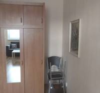 Wardrobe with a wooden decor floor in a studio apartment, cream walls, folding chairs.