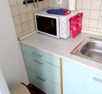 A kitchen in a studio apartment with a microwave and a sink on a spacious countertop.