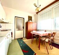 A kitchen in a studio apartment with a dining table, a patterned carpet, and a large window.