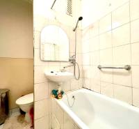 Bathroom in a studio apartment with a bathtub, sink, and toilet.