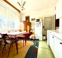 Kitchen in a studio apartment with a large window, a kitchen table, and a refrigerator.