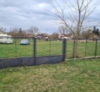 Plot surrounding a residential plot in Veľké Kosihy with a car and a trailer.