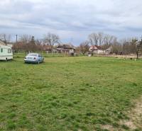 Lands - living in Veľké Kosihy with greenery, a car, and a trailer in the background.