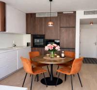 A kitchen in a 2-room apartment with a round table and chairs, flooring with a wooden decor.