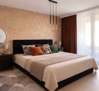 Bedroom in a two-room apartment with a large bed, mirror, and wooden decor flooring.