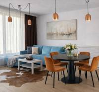 Interior of a 2-room apartment with a blue sofa, dining table, and wooden decor flooring.