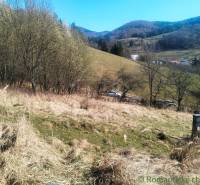 Hilly landscape in Vydrná suitable for residential plots, lined with trees and dry grass.