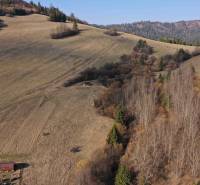 A hilly landscape of agricultural and forest land near Námestovo with a wooden structure.