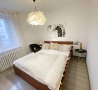 Bedroom in a 2-room apartment with a bed, armchair, and decorative lighting.