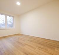 A room with a wooden floor decor and a large window in a family house.