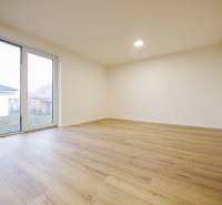 A room in a family house with a wooden decor floor and large windows.
