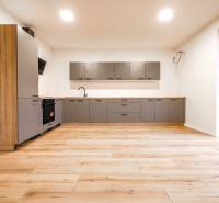 A kitchen in a family house with a wooden decor floor and large windows.