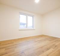 A room in a family house with a wooden decor floor and a large window.