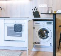 Kitchen unit with an oven and built-in washing machine in a 2-room apartment, floor with wood decor.