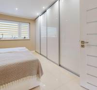A bedroom with a large built-in wardrobe and white doors in a family house.