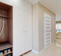 Entrance hall of a family house with a coat rack wall and cabinets with glossy white doors.