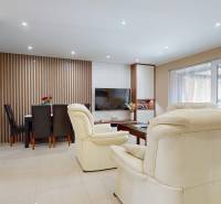 Living room in a family house with a fireplace, white sofas, and a dining table.