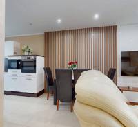 Dining room in a family house with a white kitchen and a TV on the wall.