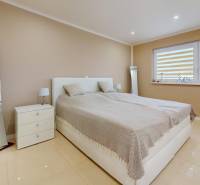 A bedroom in a family house with a large bed, a mirror, and matching furniture.