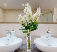 A bathroom in a family house with two sinks and decorative flowers.