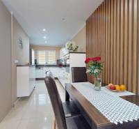 A kitchen with a dining table, wooden decor, and flowers in a family house.
