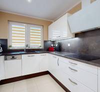 A kitchen in a family house with white cabinets, a dark countertop, and a large window.