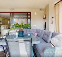 A glazed terrace of a family house with a sofa and a table, connected to the living room.