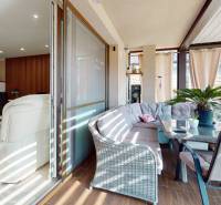 Interior of a family house with a living room, glass-enclosed terrace, and wooden decor flooring.