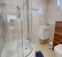 A bathroom in a family house with a corner shower, toilet, and sink.
