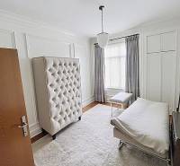 Bright bedroom in a family house with a bed, chair, and carpet on a wooden-decor floor.