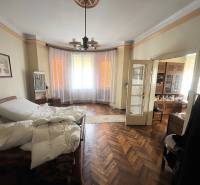 Bedroom in a family house with a bed, curtains, and a wooden decor floor.