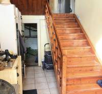Interior of a family house with a wooden staircase and a refrigerator in the background.