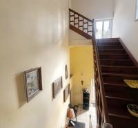 A staircase in a family house with a wooden railing and pictures on the walls.