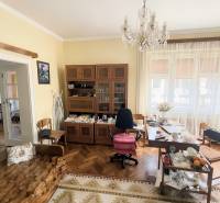 A room in a family house with a chandelier, wooden decor flooring, and furniture.