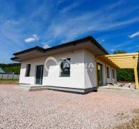 A family house in Harichovce with a sloped roof and a wooden pergola against the backdrop of a blue sky.