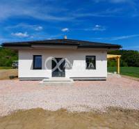 A family house in Harichovce with a white facade and a wooden pergola in the countryside.