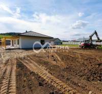 A family house in Harichovce with an uneven plot and a visible excavator on the construction site.