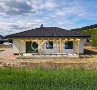 A family house in Harichovce with a terrace and garden, surrounded by nature and a blue sky.