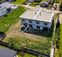 A two-story family house in Harichovce with an undeveloped plot and surrounding greenery.