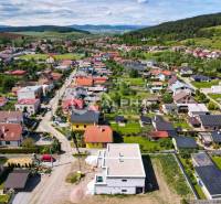 An aerial view of the residential development of family houses in Harichovce, surrounded by greenery and hills.