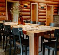 A dining room with a table and chairs, wooden walls, a floor with a wooden decor in a family house.
